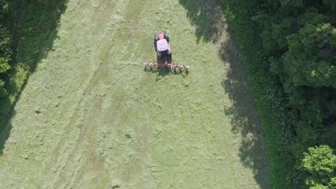 Top down drone video of a tractor mixing grass for dying before harvesting Stock Footage 312070017