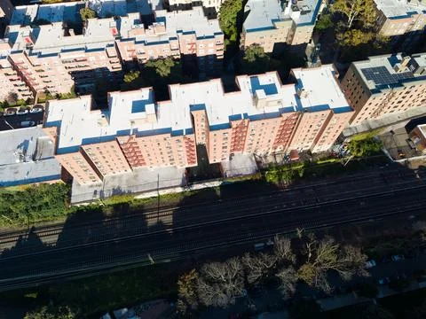 Top down drone view of brick apartment rooftops beside railway tracks Stock Photos