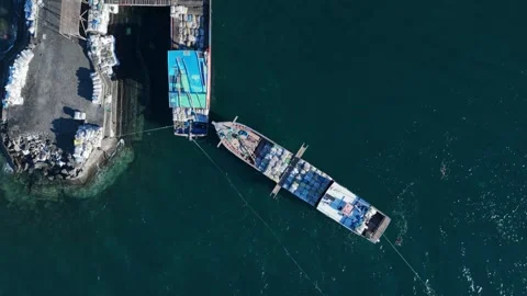 Top down drone view of cargo boat docked at harbour pier in tropical waters Stock Footage 337506040