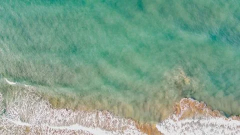 Top down drone view of clear turquoise sea water with gentle white foamy wa.. Stock Photos