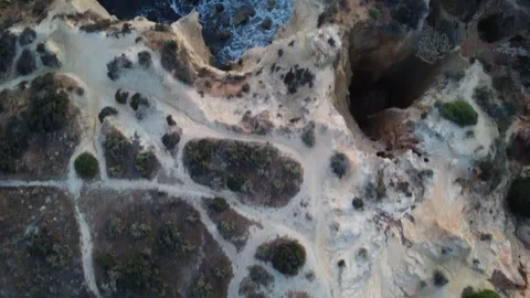 Top down drone view of cliffs with ocean waves and walking paths Stock Footage 314451762