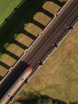 Top down drone view of a commuter train passing over Ouse Valley Viaduct Stock Photos