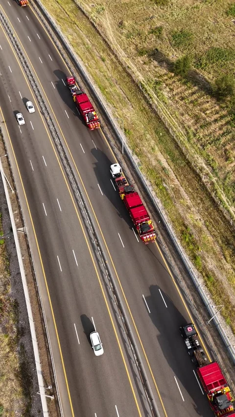 Top down drone view of convoy transporting combine harvesters on multi-lane Stock Footage 339637933