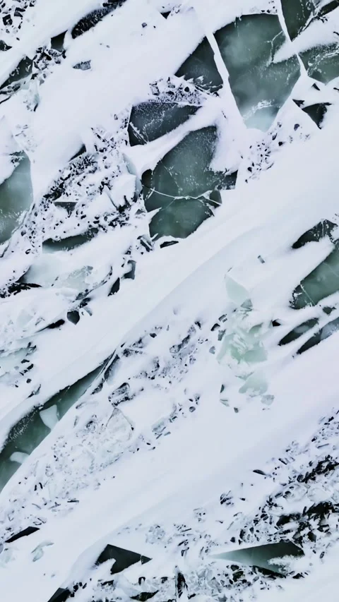 Top-down drone view of cracked sea ice covered in windblown snow streaks, with Video stock 331834658