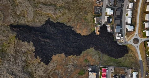 Top-down drone view of a dark lava flow reaching the residential edge of Vídeo Stock 345994623