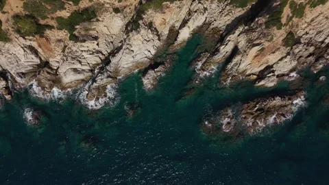 Top-down drone view of emerald waves crashing against cliffs Stock Footage 321345791