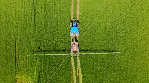 Top Down Drone View of Farmer Repairing Sprayer Beside Tractor in Green Field Video stock 329538745