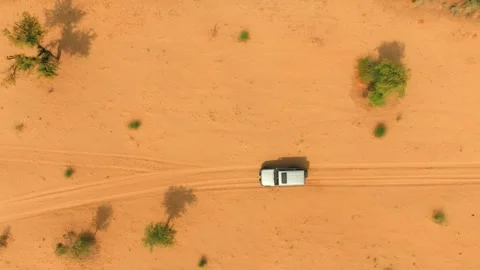 Top-down drone view of a lone 4x4 driving along parallel tire tracks across Stock Footage 345846409