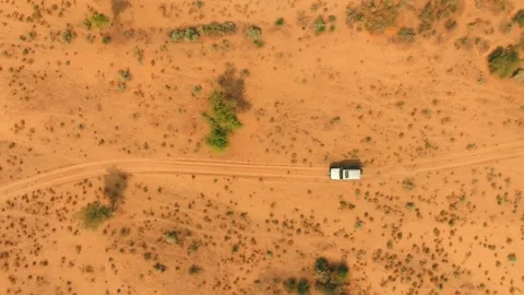 Top-down drone view of a lone 4x4 following a curving sand track through the Stock Footage 345846426