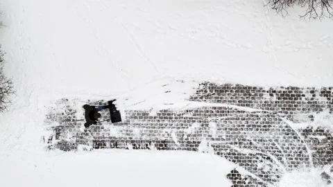 Top-down drone view of a man doing hard work, shoveling snow with work with Stock Footage 327917445