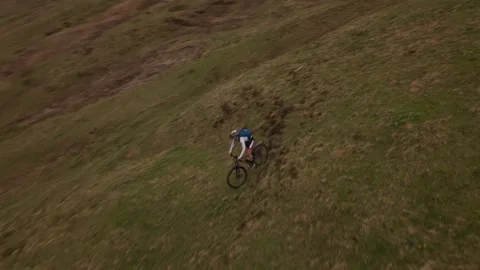 Top down drone view of mountain biker descending steep alpine terrain Видео 334626947