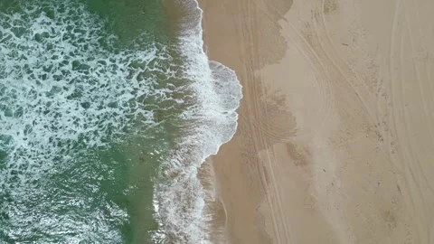 Top-down drone view of ocean waves on sand with tire tracks in Hawaii Stockbeeldmateriaal 347825968
