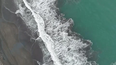 Top down drone view of Pacific Ocean waves breaking on black sand beach Video stock 338312129