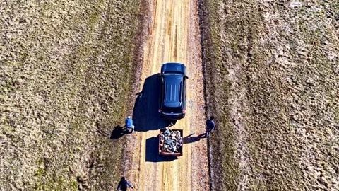 Top-down drone view of people loading fieldstones onto a trailer beside a Stock Footage 335350609