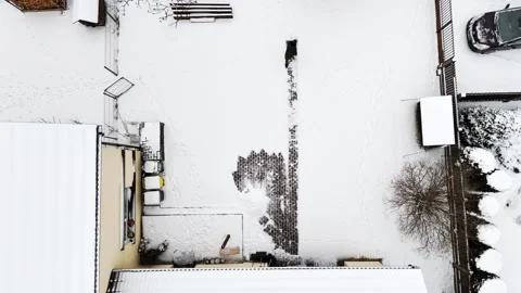 Top-down drone view of a person shoveling a narrow path through fresh snow Stock Footage 328664573