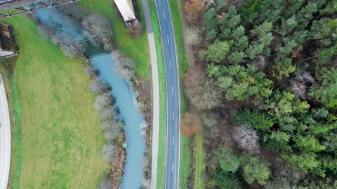 Top down drone view of a road leading under a railway bridge alongside a creek Stock Footage 224753316