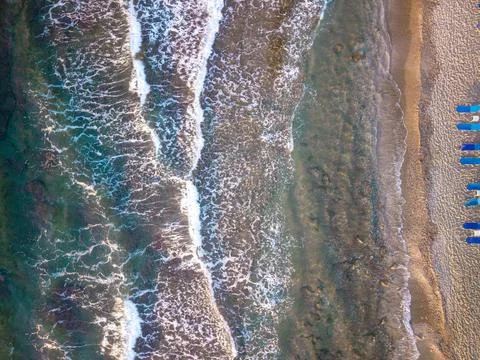 Top Down Drone View of Sea Waves and Sandy Beach with Row of Sunbeds Stock Photos
