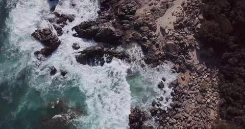 Top-Down Drone View of Sea Waves Crashing onto a Sandy Beach Shore 写真素材
