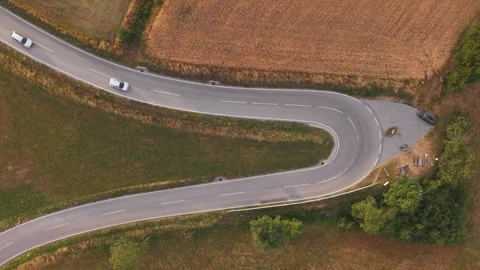 A top-down drone view of a sharp hairpin bend on a winding rural road with cars Stock Footage 339381339
