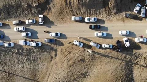 A top-down drone view shows cars lined up on a dusty rural road Stock Footage 315005635