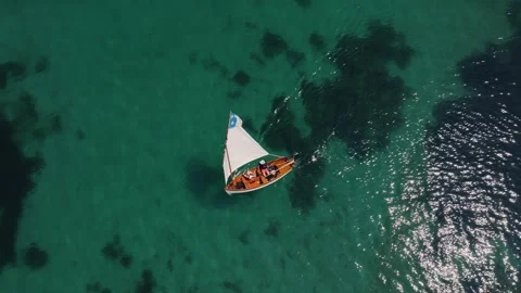 Top down drone view of small boat moving through clear green ocean water 스톡 동영상 330995400