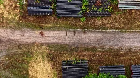 Top-down drone view of stacked black pipes beside a service road at Hambach Stock Footage 346579901
