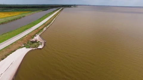 Top Down Drone View of Straight Road with Rocky Shoreline Separating Wide Lake Stock Footage 324943511