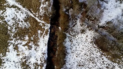 Top down drone view of stream flowing through snowy winter landscape Stock Footage 331070558