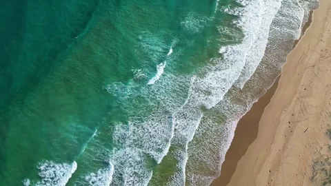 Top down drone view of turquoise ocean waves rolling toward a sandy beach Stock Footage 326972950