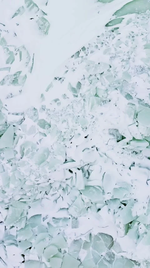 Top-down drone view of turquoise sea-ice shards and snow-covered rubble beside Stock Footage 332239689