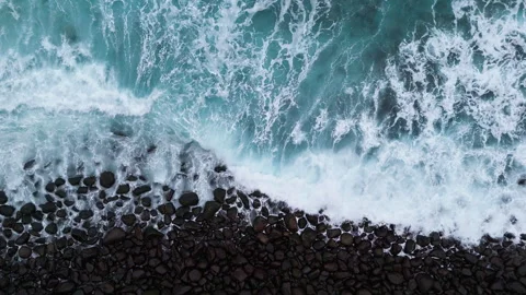 Top down drone view of waves washing over pebble beach Stock Footage 339008813