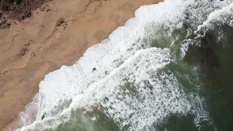Top down drone view of whitecapped waves crashing on an empty golden sand beach Stock Footage 246737794
