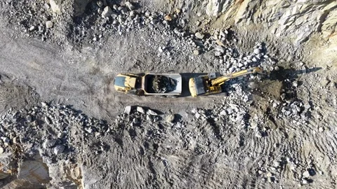 Top Down Excavator Loading Granite Rocks into Dump Truck Stock Footage 348239572