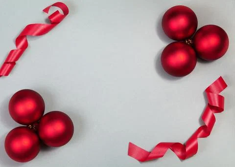 Top-down flat lay of red Christmas baubles and curled ribbon on neutral Stock Photos