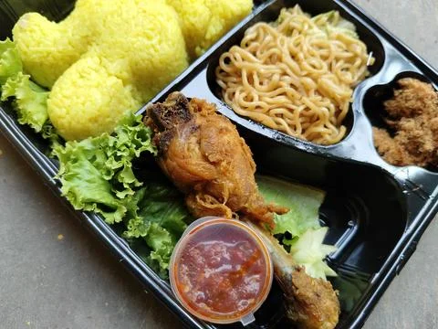Top down flat lay view of traditional Indonesian yellow rice served in a black b 写真素材