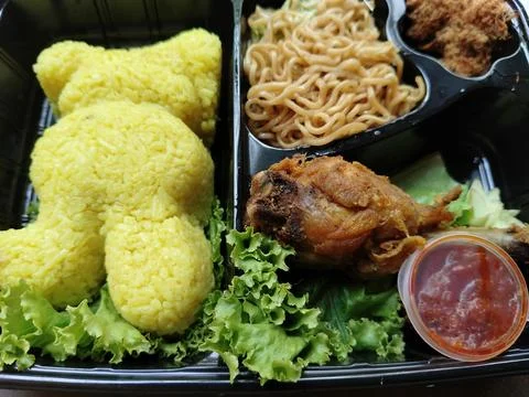 Top down flat lay view of traditional Indonesian yellow rice served in a black b 库存照片