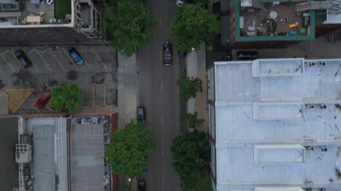 Top down flying above urban neighborhood street following single black car drivi Stock Footage 337313479