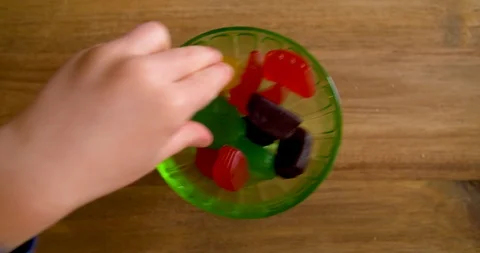 Top down footage of hands grabbing jujube candies out of a glass dish Stock Footage 106868374