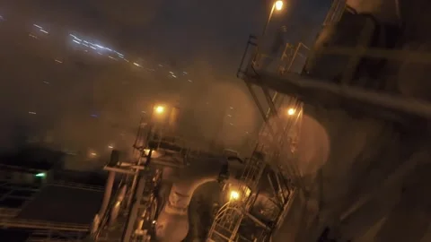 Top-down FPV drone night dive over refinery stacks, pipes and glowing lights Stock Footage 321600788