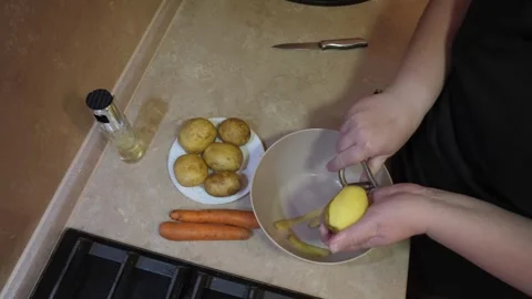 Top-down hands peeling potato into bowl 库存影片 342362698
