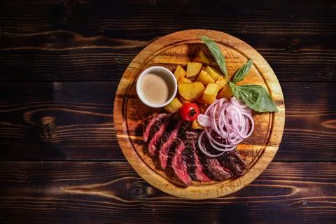 Top-down, high angle presenting sliced steak with roasted potatoes, red onion Stock Photos