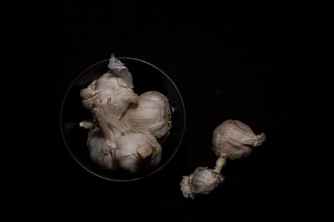 Top down image of a collection of garlic in a bowl in dark copy space backgro Stock Photos