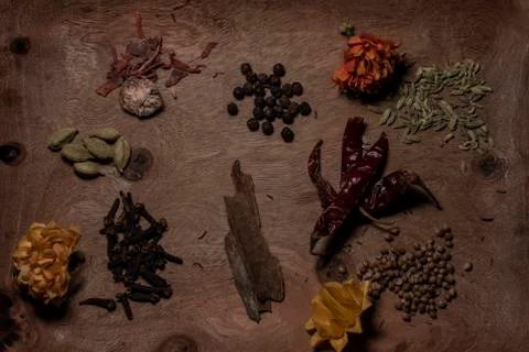 Top down image of different whole spices decorated with dried flowers in a wo Stock Photos