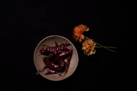 Top down image of dried red chili in a wooden bowl decorated with dried flowe Stock Photos