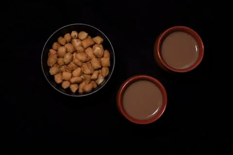 Top down image of infused tea in earthen cups along with a bowl of snacks kep Stock Photos