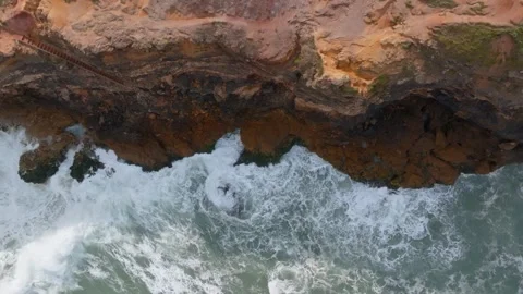 Top down left moving view of big waves of Nazare crashing on cliffs in Port.. Stock Footage 239578149