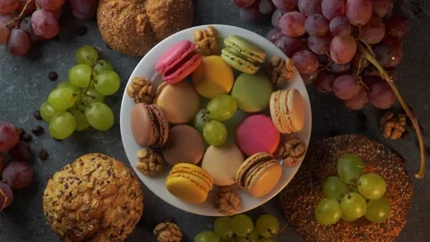 Top down loop of macarons with grapes buns coffee beans and walnuts Stock Footage 319966941