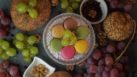 Top down loop of macarons with red grapes buns coffee beans and walnuts on .. Stock Footage 319967421