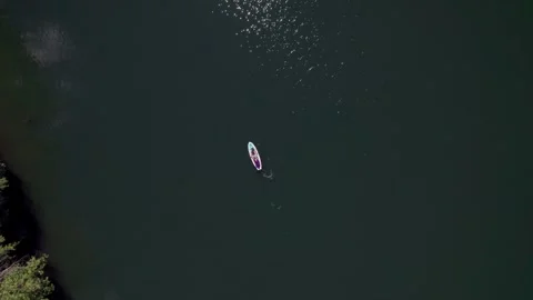 Top down of man paddle boarding on a pristine mountain lake on sunny day with Stock Footage 246610760