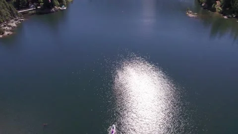 Top down of man paddle boarding on a pristine mountain lake on sunny day with Stock Footage 251684118